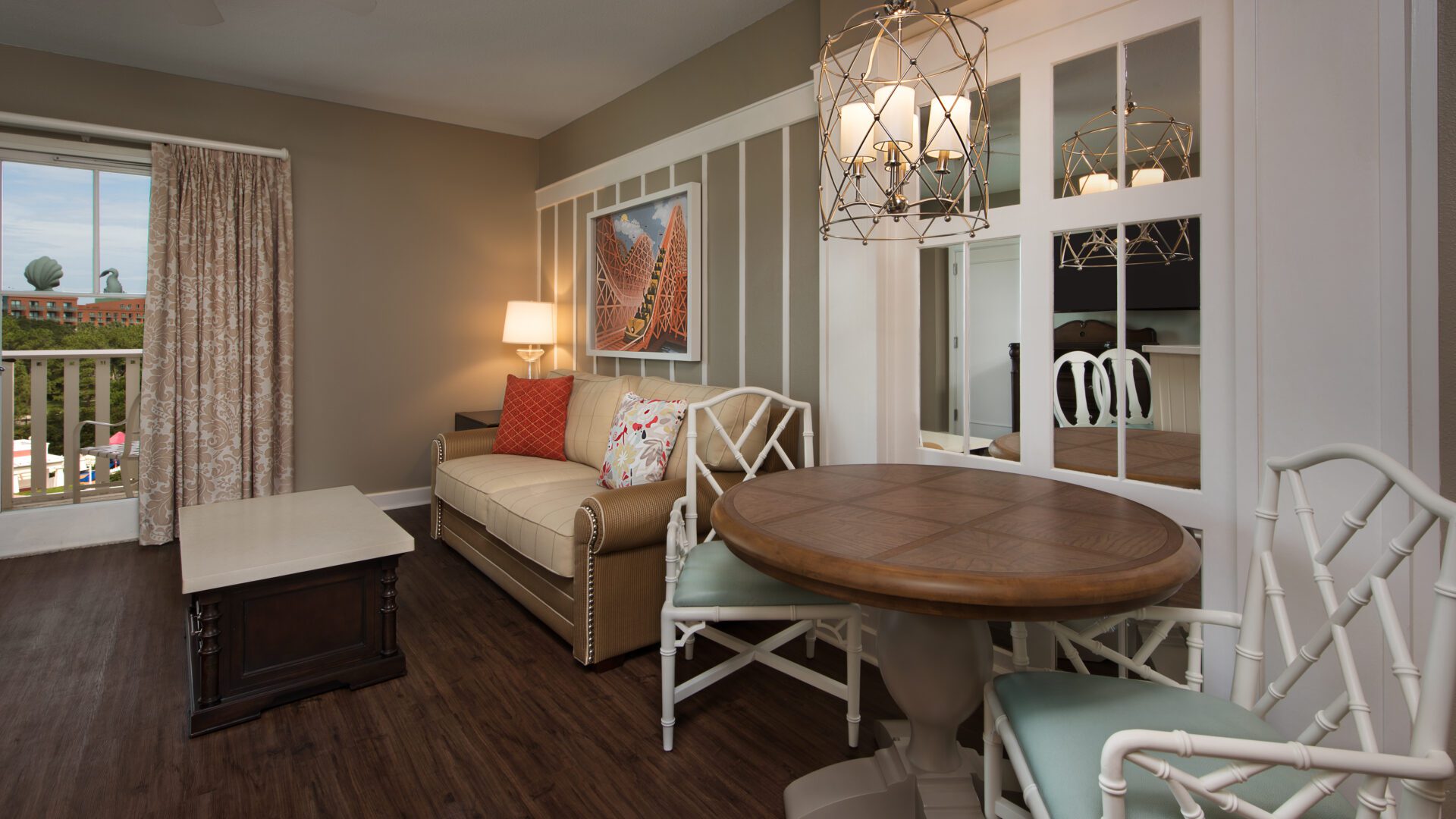 Disney Copyright Image Villas at Disney's BoardWalk Inn Villas Living Dining A cozy living space featuring a brown sofa, round dining table, and bright lamp, with large windows and warm wood flooring.