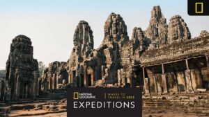 Ancient stone temples with towering spires, set against a clear sky, feature an overlay with National Geographic Expeditions branding.