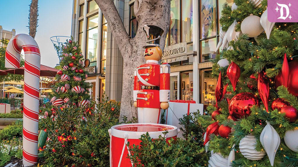 Holidays at DLR Downtown Disney A festive scene featuring a red and white toy soldier, a large candy cane, and a decorated Christmas tree with ornaments.