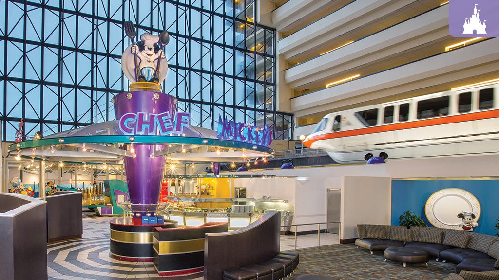 Interior view of a colorful atrium featuring a whimsical display with a cow statue, a monorail, and modern seating areas.