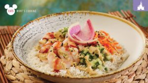A bowl of rice topped with shrimp, colorful veggies, and a garnish of pink radish, set against a textured background.