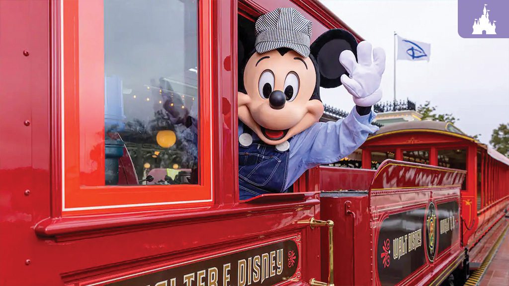 Disney World Railroad Returns Mickey Mouse, dressed as a train conductor, waves from a red train car at a theme park, with blue skies in the background.