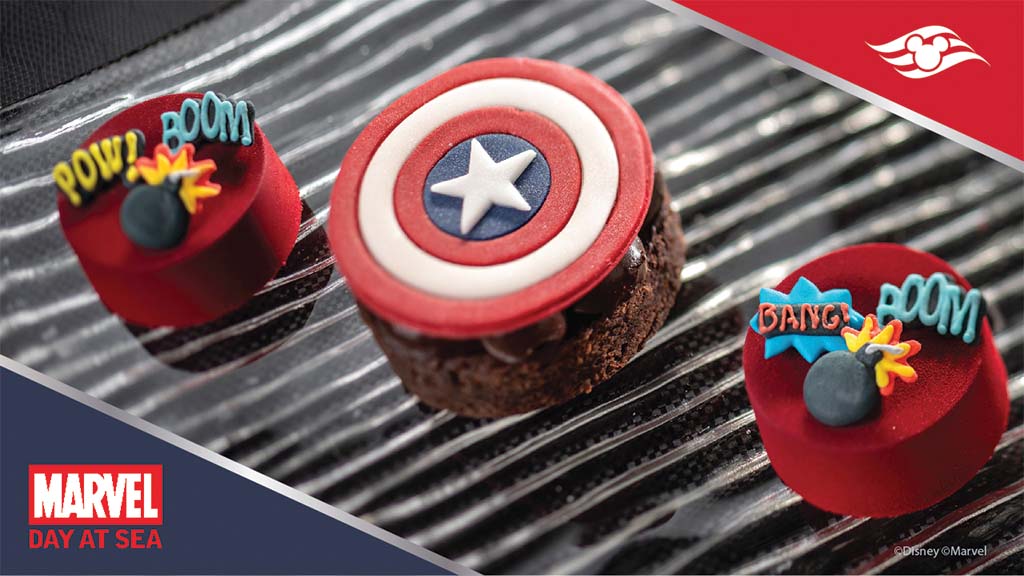 A dessert display featuring a Captain America shield cake and two round cakes decorated with comic-style "POW!" and "BOOM!" text.