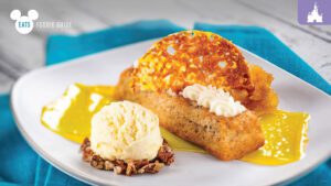 A plate featuring a dessert with a golden-brown cake slice, whipped cream, and a scoop of vanilla ice cream on a colorful sauce.