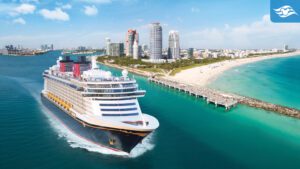 A cruise ship sails through turquoise waters near a sandy beach and a modern city skyline under a clear blue sky.