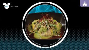 A close-up of artistic culinary dish featuring green sauce, garnishes, and red threads on a black plate against a vibrant background.