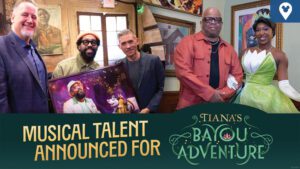 A group poses together, celebrating the announcement of musical talent for "Tiana's Bayou Adventure," featuring a character in a green dress.