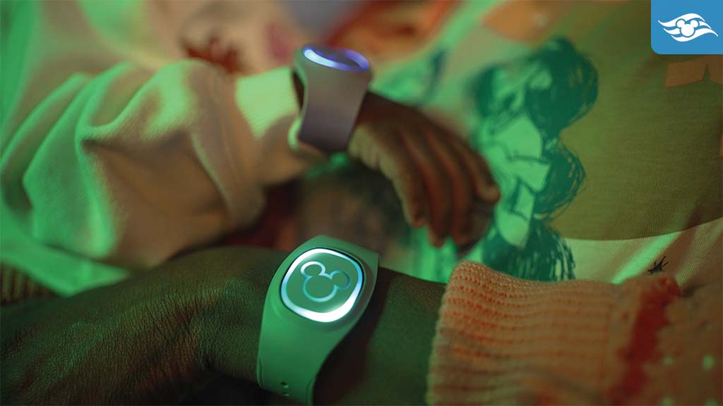 Close-up of a parent and baby's wrists wearing glowing wristbands in a softly lit environment, showcasing a connection between them.