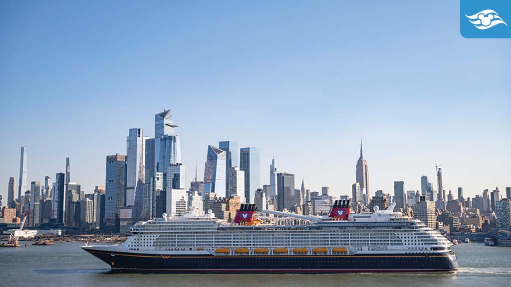 Large cruise ship with red funnels featuring a mouse-ear silhouette sailing in front of a city skyline of glass skyscrapers