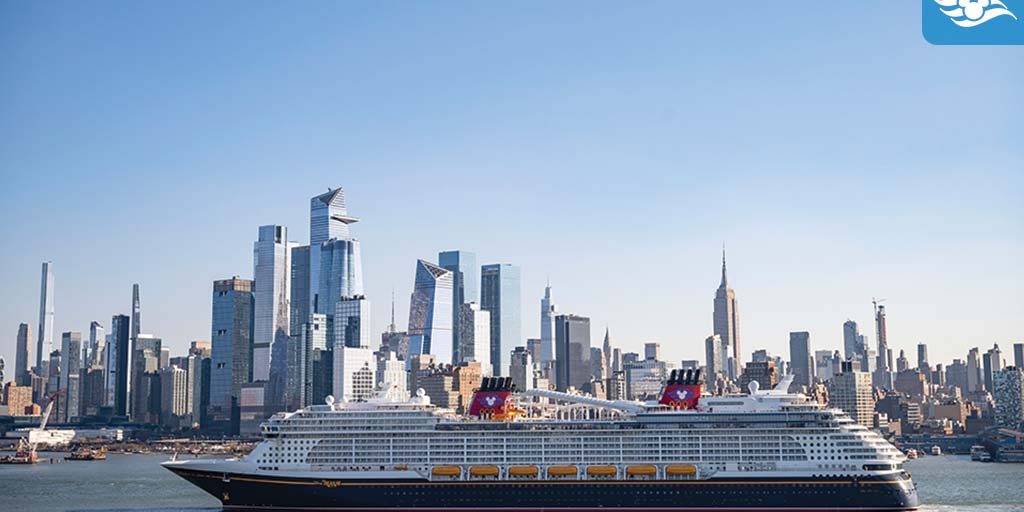 Large cruise ship with red funnels featuring a mouse-ear silhouette sailing in front of a city skyline of glass skyscrapers
