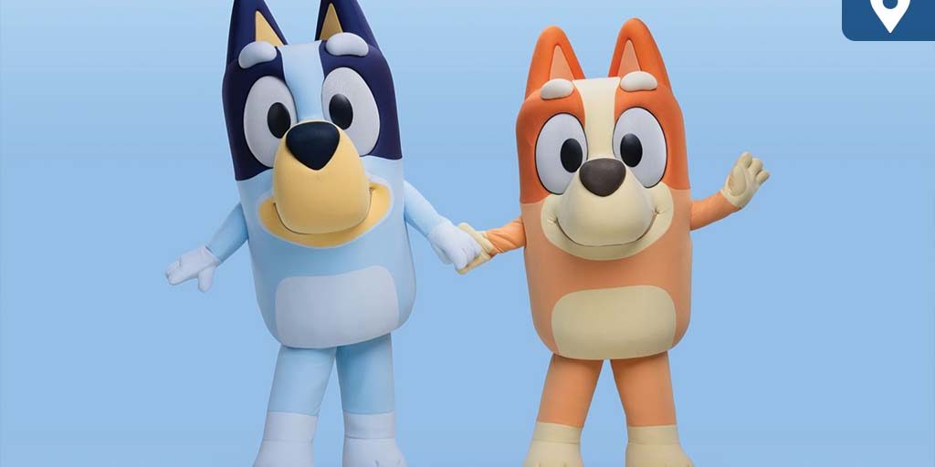 Bluey and Bingo characters holding hands and smiling against a light blue background.