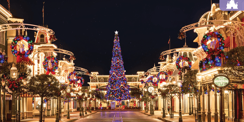Towering Christmas tree glows with lights on Main Street, U.S.A. at Magic Kingdom, framed by wreaths and holiday decor.