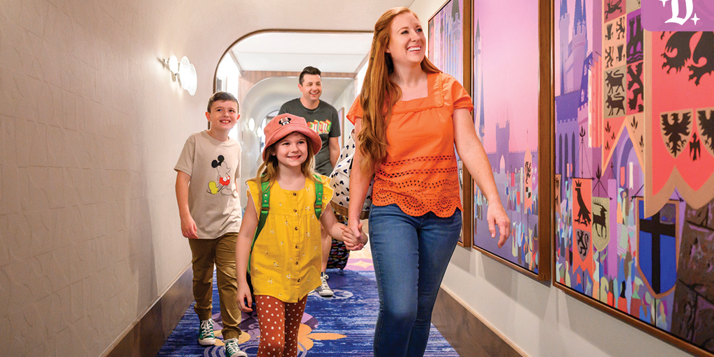 Smiling family walks through a colorful Disneyland Resort Hotel hallway decorated with castle-themed artwork.