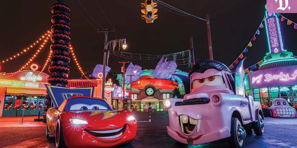Lightning McQueen and Mater dressed in Halloween costumes in Radiator Screams at Disney California Adventure, surrounded by colorful neon lights and spooky decorations.