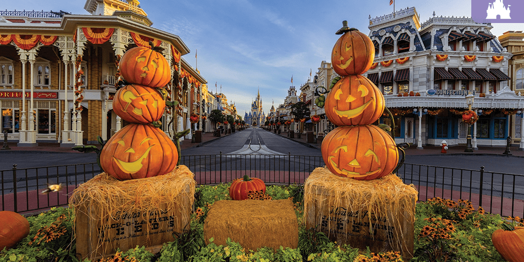 Stacked jack-o'-lanterns on hay bales line Main Street, U.S.A. at Magic Kingdom, with Cinderella Castle visible in the background during fall.