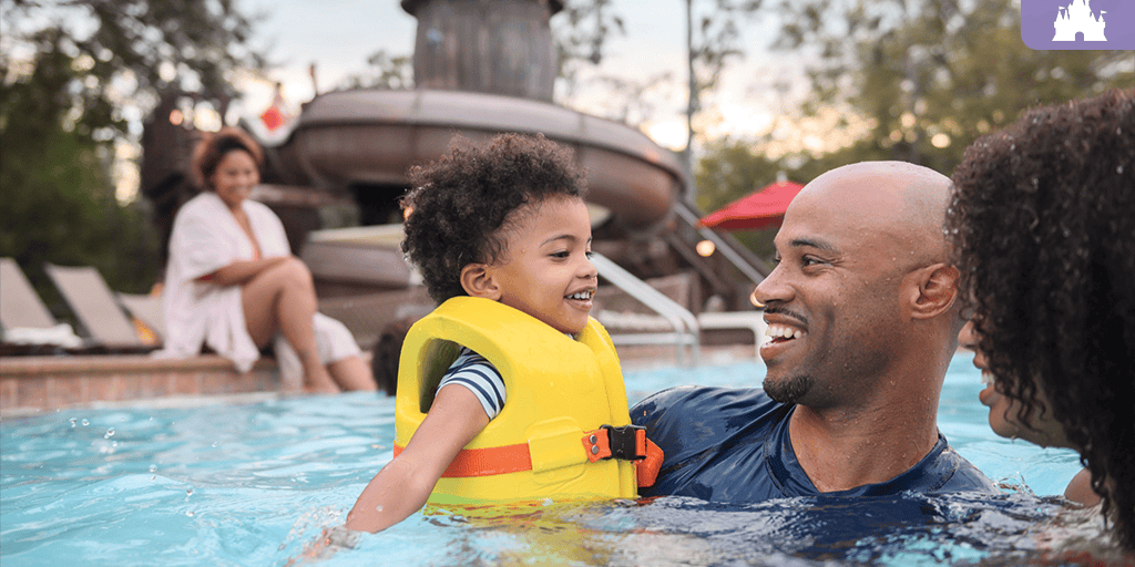 Family enjoys the Meadow Swimmin' Pool at Fort Wilderness, with the corkscrew waterslide visible in the background.