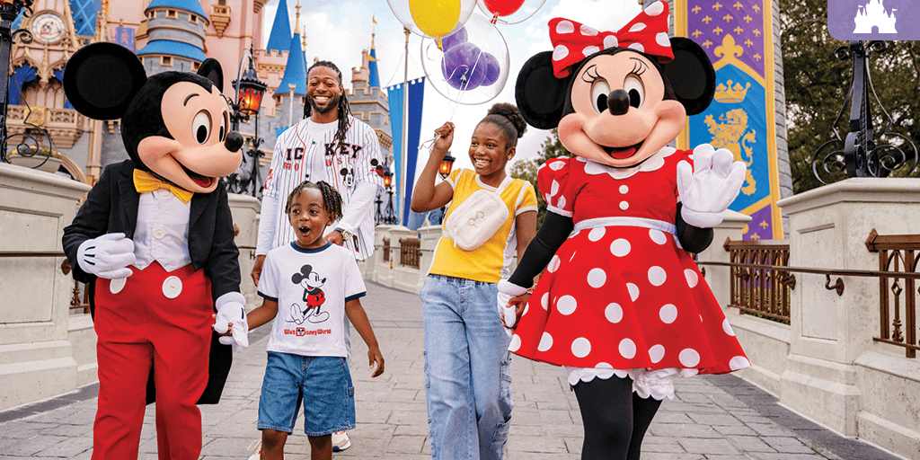 A smiling family walks with Mickey and Minnie Mouse at Walt Disney World, holding balloons in front of Cinderella Castle.