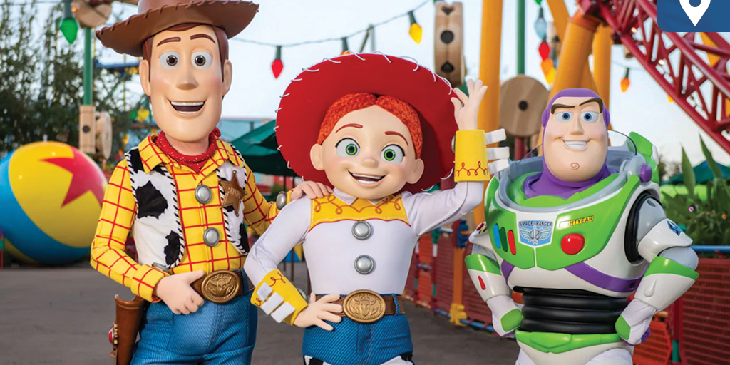 Woody, Jessie, and Buzz Lightyear posing together in Toy Story Land with colorful rides in the background