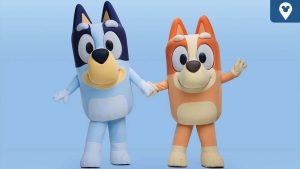 Bluey and Bingo characters holding hands and smiling against a light blue background.