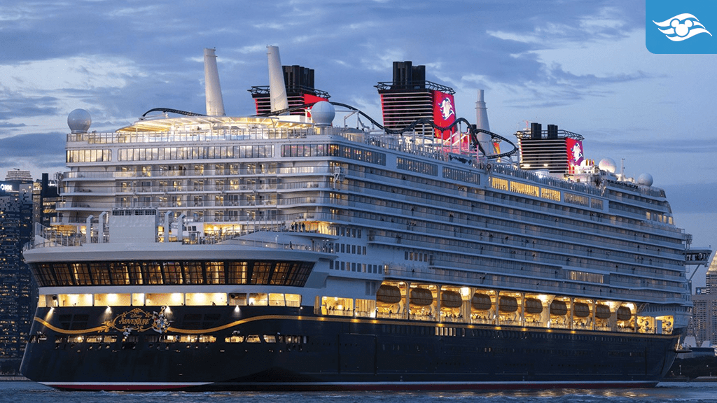 Disney Adventure cruise ship docked at dusk with glowing decks and onboard roller coaster visible above the skyline in Singapore.