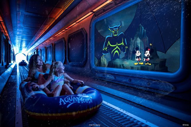 Two girls sit in an inflatable ride, enjoying a colorful underwater scene with animated characters on a screen in a dimly lit setting.