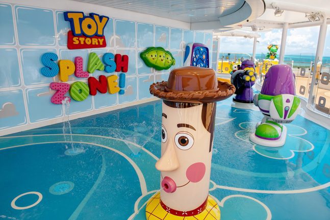 Colorful splash zone featuring Toy Story characters, with a large Woody figure and vibrant play areas. Water features and fun decor.