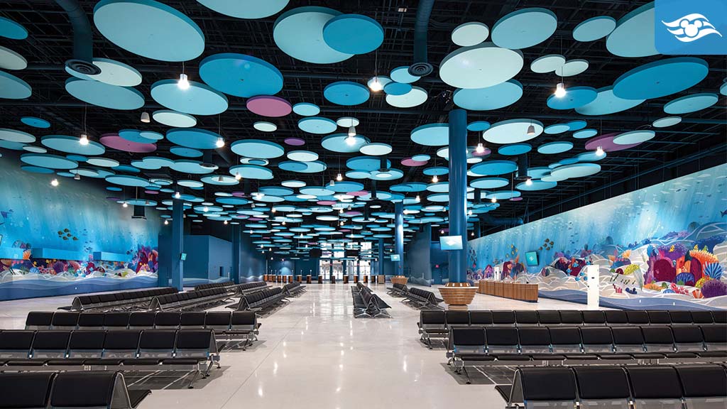 A spacious waiting area with sleek black benches, featuring a vibrant ceiling of colorful circles and blue mural walls, creating a lively atmosphere.