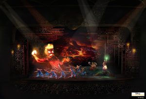 A vibrant stage scene depicting dancers in costumes performing with a large, fiery figure projected in the background, illuminated by spotlights.