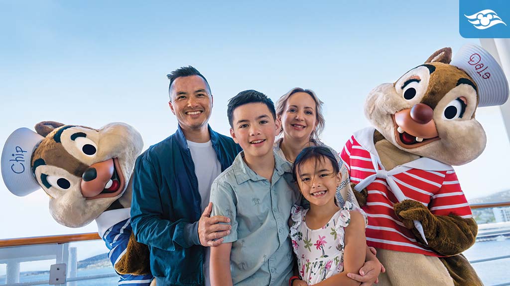 Family posing with Chip and Dale in sailor outfits on a Disney Cruise ship deck with ocean views.