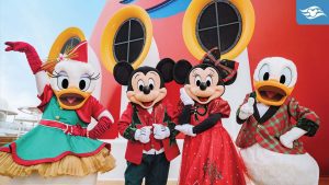 Disney characters Daisy Duck, Mickey Mouse, Minnie Mouse, and Donald Duck in festive holiday outfits on a Disney Cruise ship.