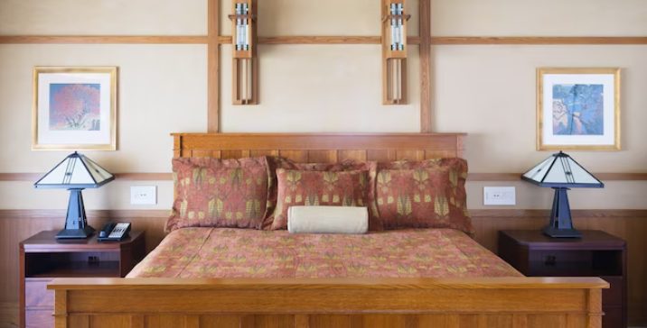 A cozy bedroom featuring a wooden bed with decorative pillows, framed artwork on the walls, and bedside lamps on wooden nightstands.