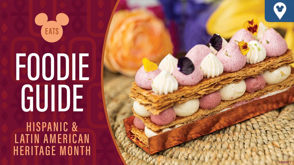 A layered pastry topped with pink and white cream, garnished with edible flowers. Text reads "Foodie Guide: Hispanic & Latin American Heritage Month."