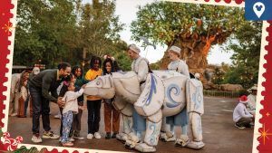 A family interacts with a life-sized, handcrafted polar bear puppet near the Tree of Life at Disney's Animal Kingdom. Puppeteers dressed in festive costumes bring the wintry animal to life, creating a magical holiday moment.