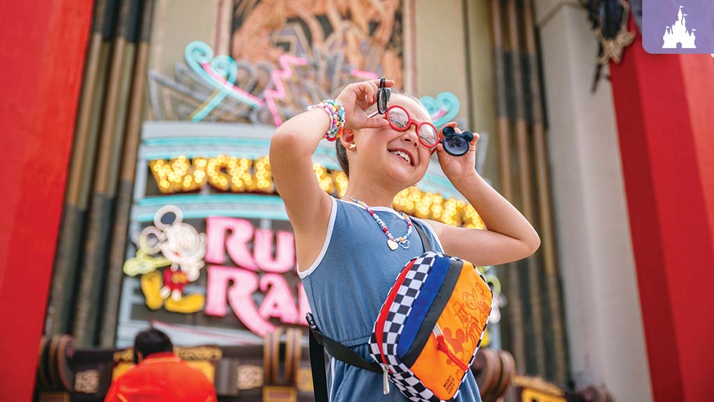 Child smiling and holding Mickey-shaped glasses at Mickey & Minnie's Runaway Railway at Disney's Hollywood Studios.
