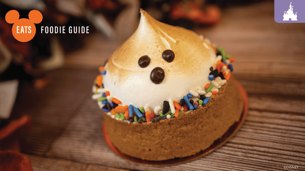 disney-world-halloween-foodie-treats A decorated dessert featuring a swirled meringue topping, chocolate eyes, and colorful sprinkles on a brown base, styled for Halloween.