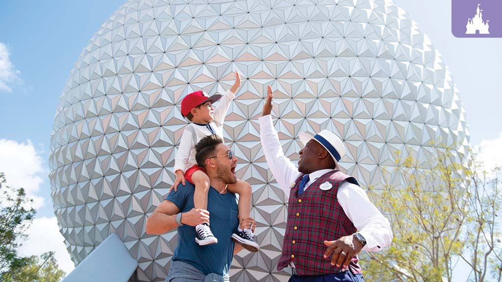 A Disney Private VIP Tour Guide gives a high-five to a child sitting on a man's shoulders in front of EPCOT's Spaceship Earth.