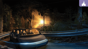 Guests ride through a forest-themed scene in a futuristic car on the reimagined Test Track at EPCOT, illuminated by glowing lights.