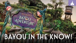 A colorful sign reads "Tiana's Bayou Adventure," surrounded by lush greenery and a vintage water tower in the background.