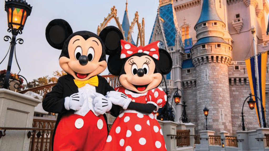 disney-wrold-mickey-minnie-mouse-cinderella-castle Mickey and Minnie Mouse pose together in front of a fairy-tale castle, smiling and dressed in their iconic outfits.