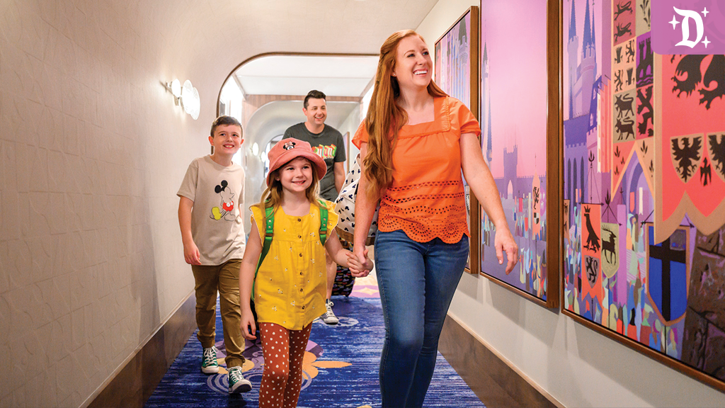 Smiling family walks through a colorful Disneyland Resort Hotel hallway decorated with castle-themed artwork.