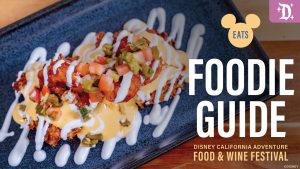 A close-up of a plate featuring gourmet food topped with sauce and vegetables, with a text overlay for the Disney California Adventure Food & Wine Festival.