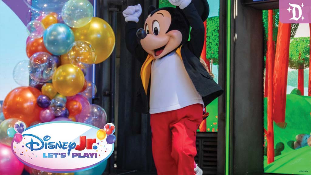 disneyland-disney-jr-lets-play-2025 Mickey Mouse dancing on stage at Disney Jr. Let’s Play!, surrounded by colorful balloons and vibrant forest-themed decor.