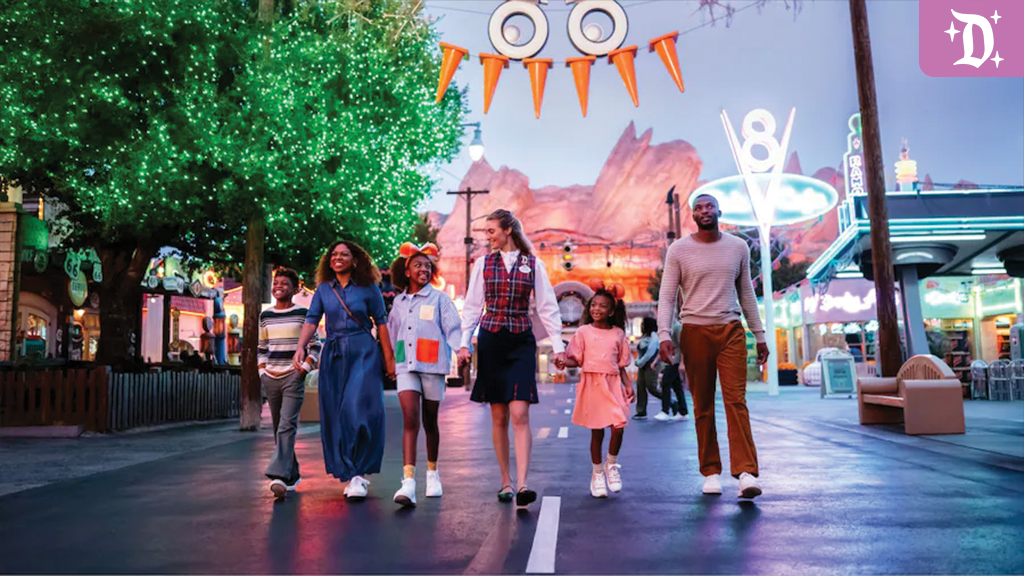 disneyland-oogie-boogie-bash-vip-2025 A family walks with a Disney VIP tour guide through a festively decorated Cars Land at Disney California Adventure during Oogie Boogie Bash, with Halloween lights and ornaments glowing.