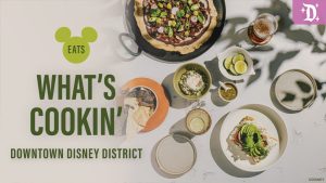A flat lay of various dishes and drinks, with text overlay announcing "What's Cookin' Downtown Disney District" and a Mickey Mouse logo.