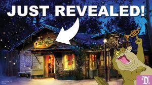 A rustic cabin is shown at dusk with "JUST REVEALED!" text. A cartoon character enthusiastically plays a trumpet beside the cabin.