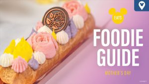 A beautifully decorated dessert featuring pastel flowers, a chocolate medallion, and the text "Foodie Guide Mother's Day" against a pink background.