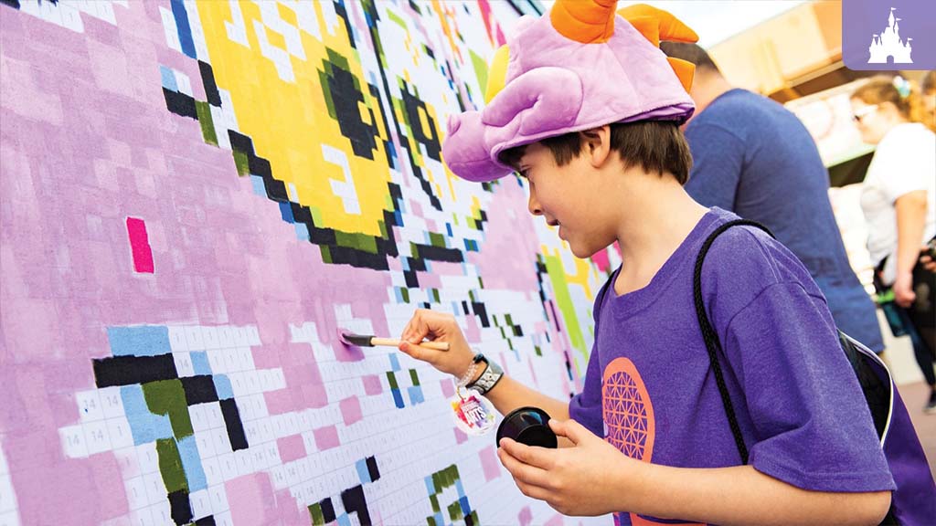 Child painting a color-by-number mural at EPCOT Festival of the Arts while wearing a Figment hat and purple shirt.