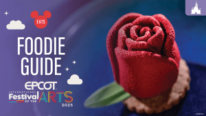 Close-up image of a stunning dessert shaped like a vibrant red rose, set against a dark, elegant background. The graphic features the text "Foodie Guide" and branding for the EPCOT International Festival of the Arts 2025.
