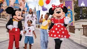 A smiling family walks with Mickey and Minnie Mouse at Walt Disney World, holding balloons in front of Cinderella Castle.