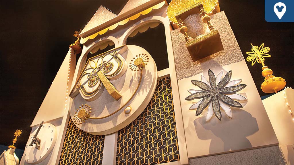 Close-up of the golden clock facade from Disney's “it’s a small world” attraction, featuring geometric patterns and whimsical flower designs.